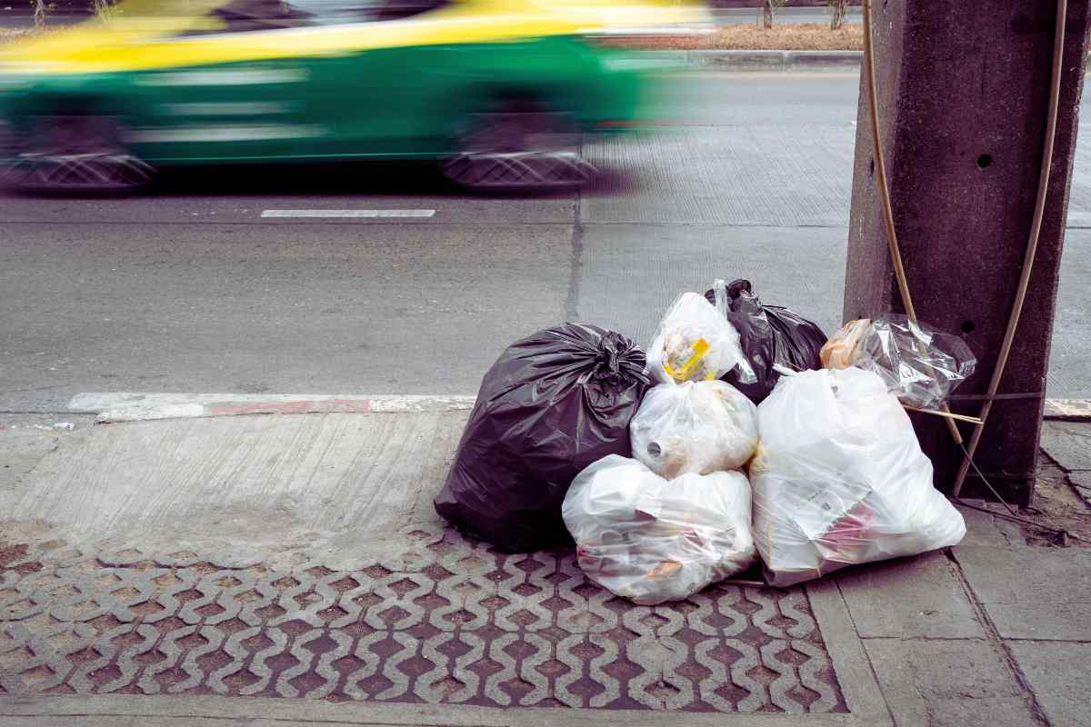 sacchetti della spazzatura ammucchiati ai lati della strada